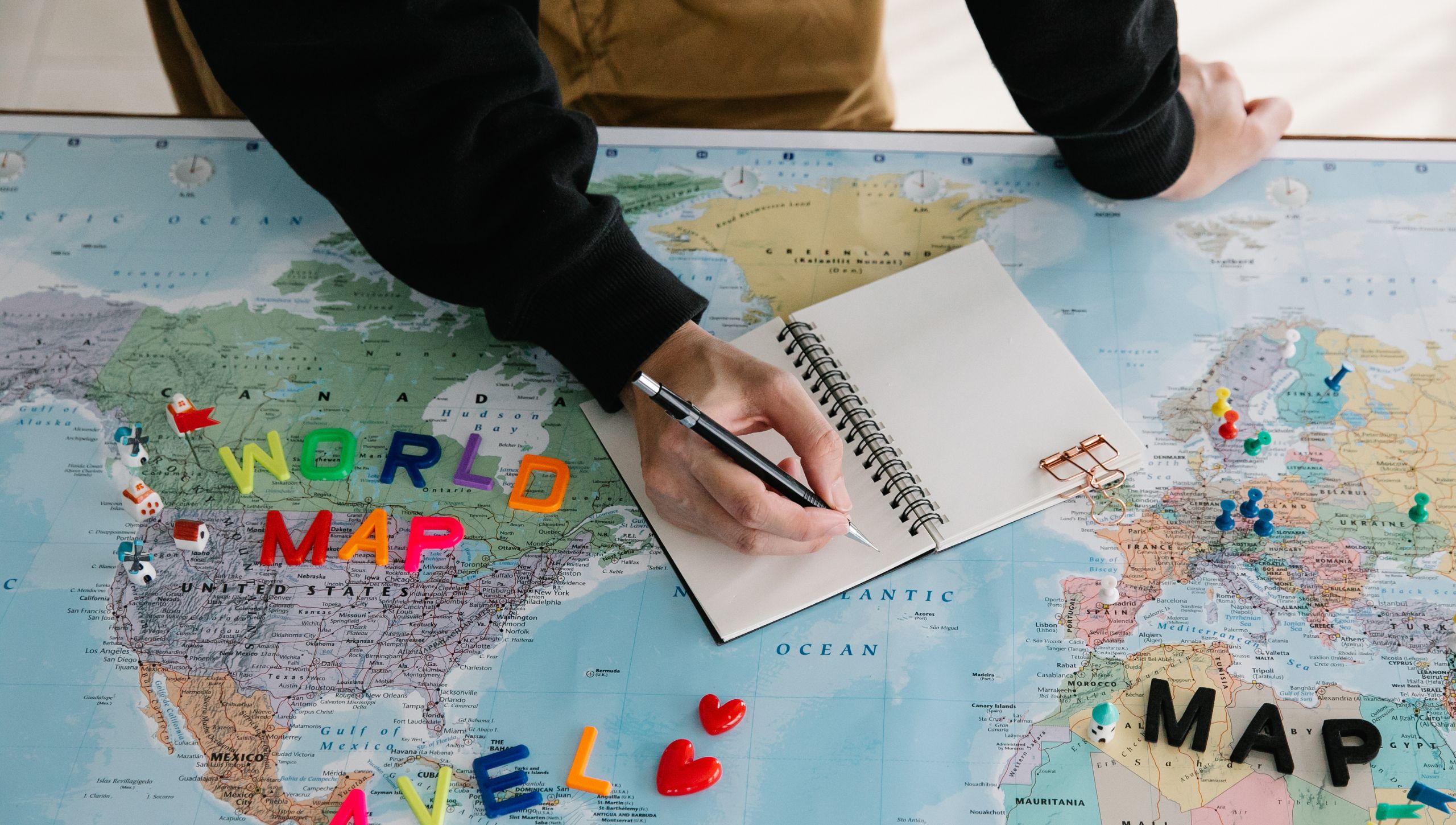 Person Writing in a Journal on Top of a World Map